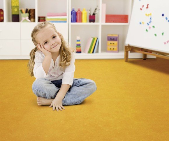 Happy little girl in her room sitting on the floor smiling